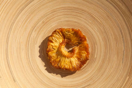 Slice of dried pineapple on a round wooden plate. Healthy natural sweets. Top view, copy space.の写真素材