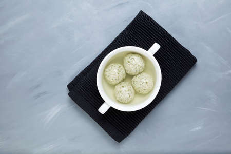 Turkey meatballs with spinach in bone broth in a white bowl on a black linen napkin. A healthy...