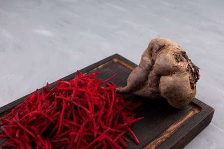 Whole ugly beetroot and grated beets on a dark cutting board. Selective focus. Crooked vegetables of abnormal shape can be eaten. Concept - Food waste reduction. Using in cooking imperfect products.の写真素材