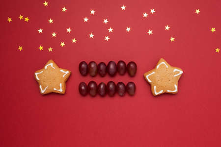 Christmas cookies in the shape of stars and grapes on a red background with copy space. New year...