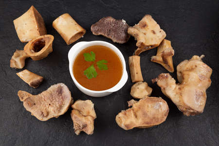 Homemade Beef Bone Broth in white bowl on a dark stone background. Bones contain collagen, which...