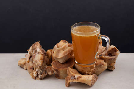 Transparent Cup of bone broth is placed on boiled beef bones, which contain the necessary amino acids for the body. Selective focusの写真素材