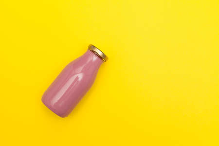 Pink glass bottle with golden lid on yellow background with copy space. Healthy fruit drink with collagen.の写真素材