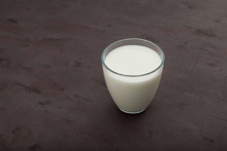 Ayran or kefir in a glass on brown background. Fermented milk ayran. Milk diet for weight loss. Selective focus, copy space.の写真素材