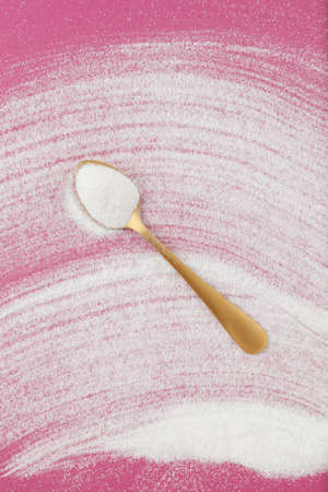 Collagen in golden spoon. Powder scattered on pink paper background. Place for text.の写真素材