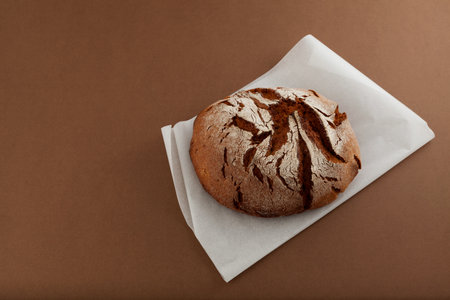 Fresh homemade crisp bread on brown background. French bread at leaven. Place for text.