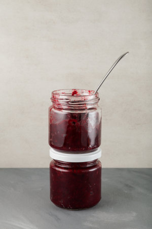 Two glass jars of fried or stewed beets stand on top of each other. Vertical orientation, copy...