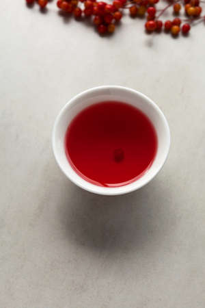 Schizandra tea in white tea cup, selective focus. Traditional Oriental drink is brewed from Chinese lemongrass berries. Used in alternative medicine.の写真素材