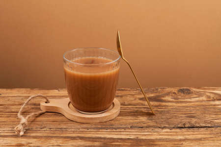 Indian tea in glass. It is brewed of strong sweetened black tea with milk or condensed milk, often...