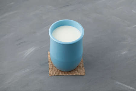 Fermented milk drink. Turkish drink Ayran or kefir in blue ceramic jug on gray background. Diet...