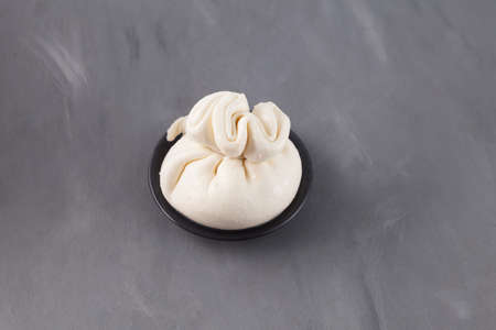 Soft pouch of Italian cheese. Burrata or burratina cheese made from mozzarella and cream filling. Selective focus, gray background, copy space.の写真素材