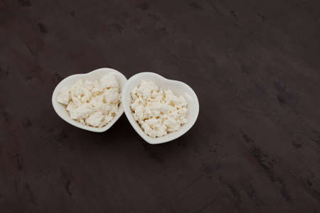 Cottage cheese in white bowls in shape of hearts. Organic eco healthy food. Natural dairy product. Selective focus, copy space.の写真素材