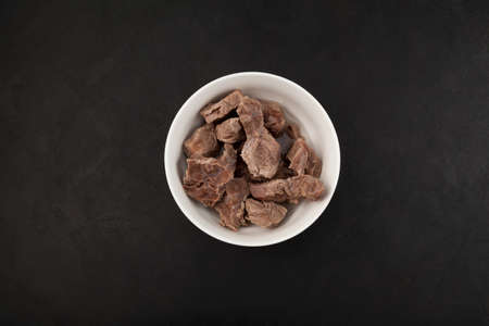 Pieces of beef or lamb in white bowl, top view. Dietary boiled meat. Dark background, space for text.の写真素材