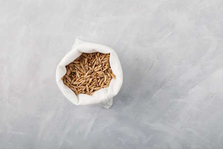Whole grain oats in white bag, top view. Gray background, copy space.の写真素材