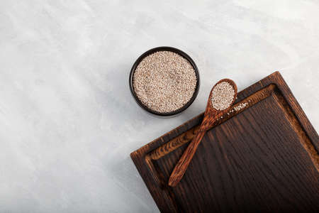 Seeds Chia white in wooden spoon on brown cutting board.