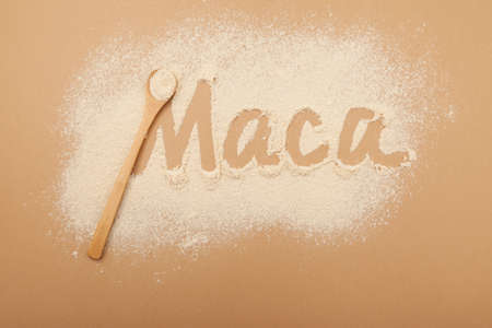 Inscription Maca of Maca gelatinized flour on beige background. Bamboo spoon with powder, top view, design element. Peruvian superfood, natural organic supplement.の写真素材