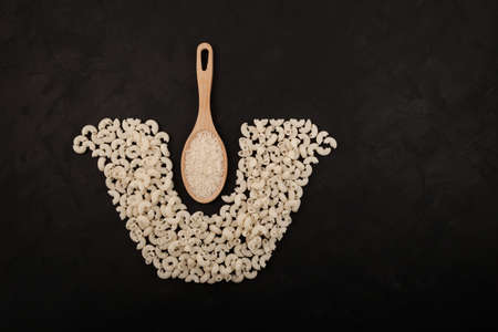 Healthy gluten-free pasta made from rice flour. Wooden spoon with rice. White pasta laid out in the...