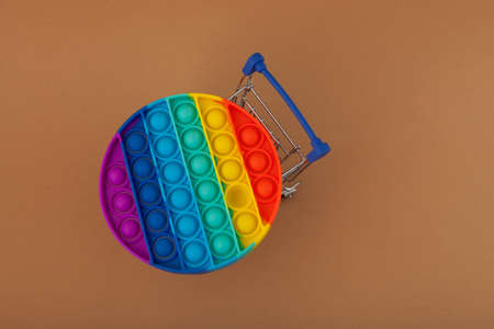 Silicone colorful anti stress pop it toy for child in grocery trolley. Top view. Beige background, copy space.の写真素材