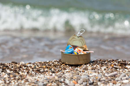 Tin can filled with plastic garbage collected on the beach. Concept - excessive consumption of...