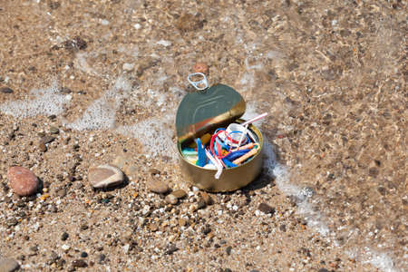 Tin can filled to the top with plastic waste and garbage collected on beach. Coastline. Concept -...