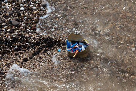 Plastic garbage and tin can on seashore. Household waste and disposable plastic waste on beach. Sea...