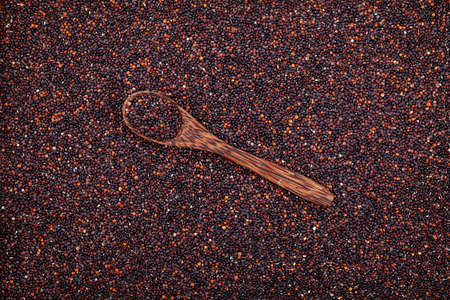 Black organic quinoa or Ragi seeds in a wooden spoon lie on top of groats, top view. Organic Cereals...