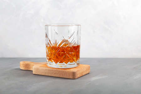 Whiskey on the rocks or scotch with ice cubes. Old fashion glass. Gray background, copy space.