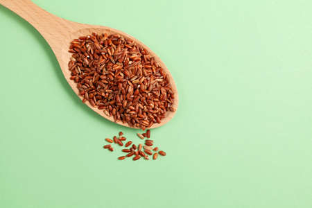 Brown GABA rice in wooden spoon on green background, close-up. Selective focus, copy space.の写真素材