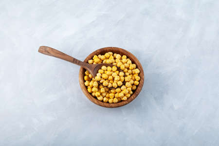 Leblebi or Roasted Chickpea in wooden spoon and wooden bowl on gray background. Turkish healthy snack. Selective focus, copy space.の写真素材