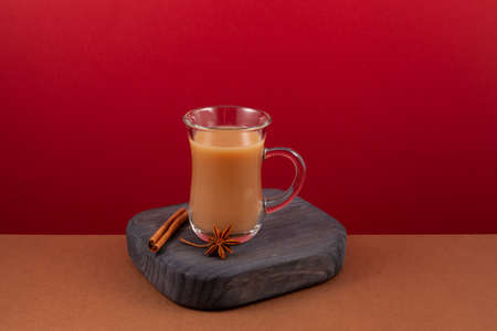 Cup aromatic Indian milk tea. Karak tea or masala chai on red background.の写真素材