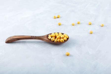 Leblebi or Roasted Chickpea in wooden spoon on gray textured table. Turkish healthy snack. Selective focus, copy space.の写真素材