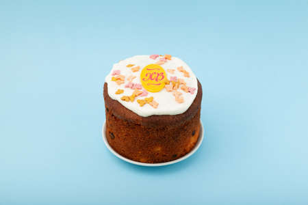 Glazed easter cake decorated with candied fruits on light blue background. Happy Easter Holidays.