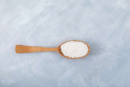 White tapioca pearls in wooden spoon on gray background. Tapioca balls or sago balls use for bubble tea, boba drinks and refreshments cocktails.の写真素材