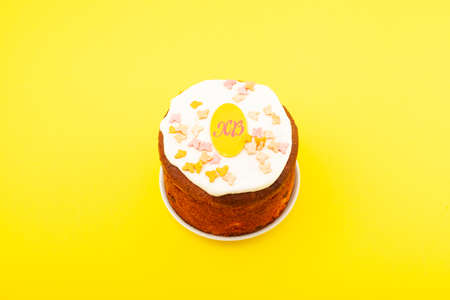 Glazed easter cake decorated with candied fruits. Yellow background, copy space.