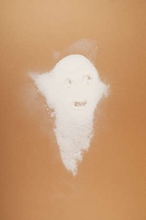 Pile of white powder in the shape of ghost on beige background. Concept of harmful food and food additives.の写真素材