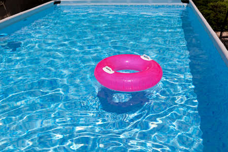 Frame outdoor swimming pool. Inflatable swimming circle on the water surface. Summer, sunny day.