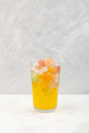Boba drink or fruit bubble tea. Refreshing cocktail with fruits ice cubes on gray textured background. Selective focus, copy space.の写真素材