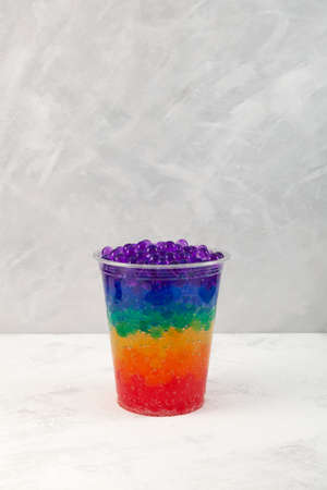 Multicolored Boba drink or Rainbow bubble tea in disposable plastic cup. Refreshing summer cocktail...