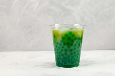 Green Boba drink or bubble tea with Moringa and Matcha. Refreshing cold cocktail in disposable plastic cup.の写真素材