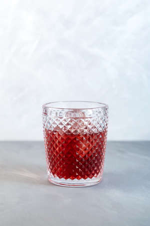 Glass of Americano Alcohol cocktail with red vermouth, bitter, soda water and ice cubes on gray...