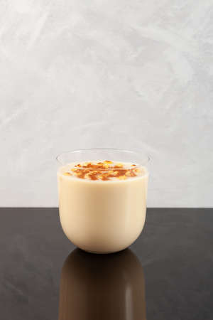 Boza or Bosa in clear glass. Traditional Turkish fermented drink with roasted chickpeas and cinnamon powder. Vertical orientation, copy space.の写真素材