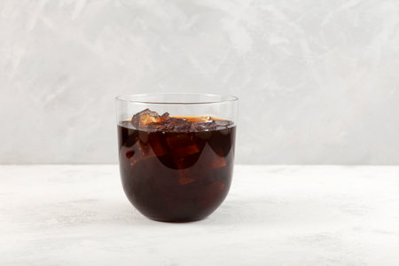 Cold iced coffee cocktail in clear glass. Refreshing summer alcoholic drink. Gray background, copy...