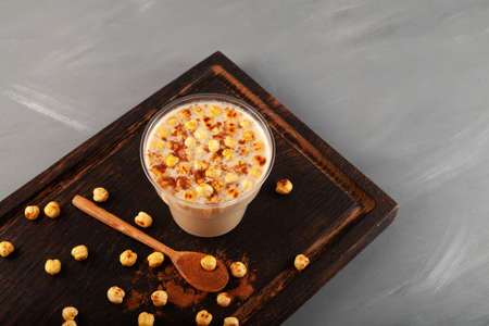 Boza or Bosa in disposable plastic cup. Tradition Turkish fermented drink with roasted chickpea and cinnamon powder.の写真素材