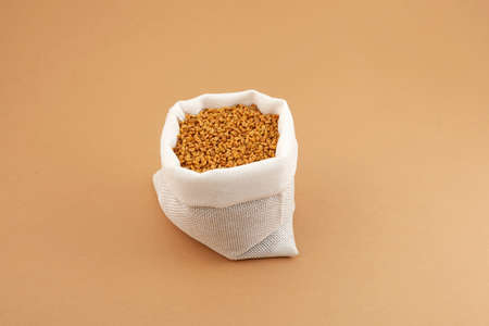 Fenugreek Seeds in white pouch on beige background. Shambhala or helba seeds is traditional Indian seasoning and ingredient Ayurvedic food.の写真素材