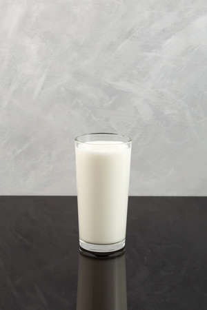 Buttermilk or Kefir in tall clear glass. Fermented milk ayran. Milk diet for weight loss. Gray background, copy space.の写真素材