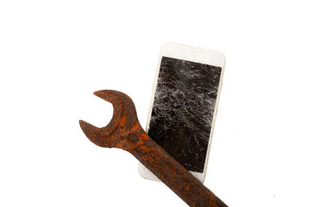 Rusty wrench and broken phone screen. Smartphone glass with numerous cracks. Faulty gadget. Funny...