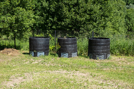 Three compost container bins in the countryside. Black Plastic tanks with organic biodegradable food...