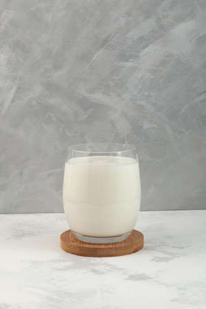 Sour milk drink. Ayran or kefir in clear glass on gray background. Fermented milk ayran. Milk diet for weight loss.の写真素材