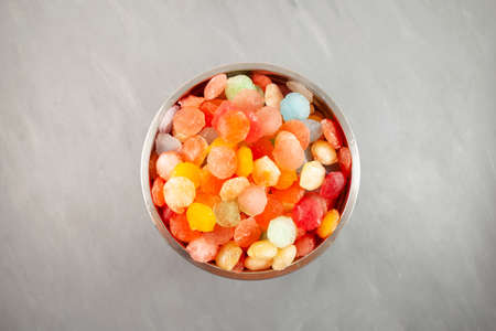 Colored ice cubes in metal container, top view. Frozen fruit juice. Rainbow ice for cocktails,...