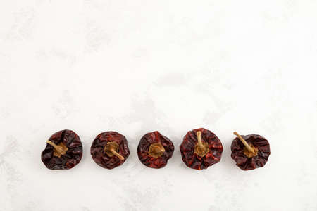 Row of Dried Spanish Nora Peppers on gray textured background. Top view, copy space.